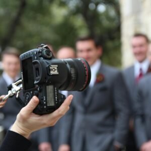 man in black suit holding black nikon dslr camera
